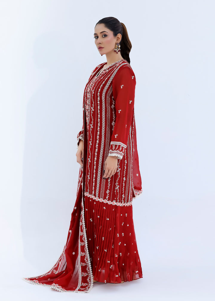 Woman wearing a red traditional outfit with white patterns on a white background